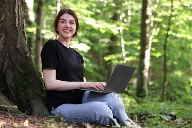 Smiling freelancer working with laptop in forest. Remote job