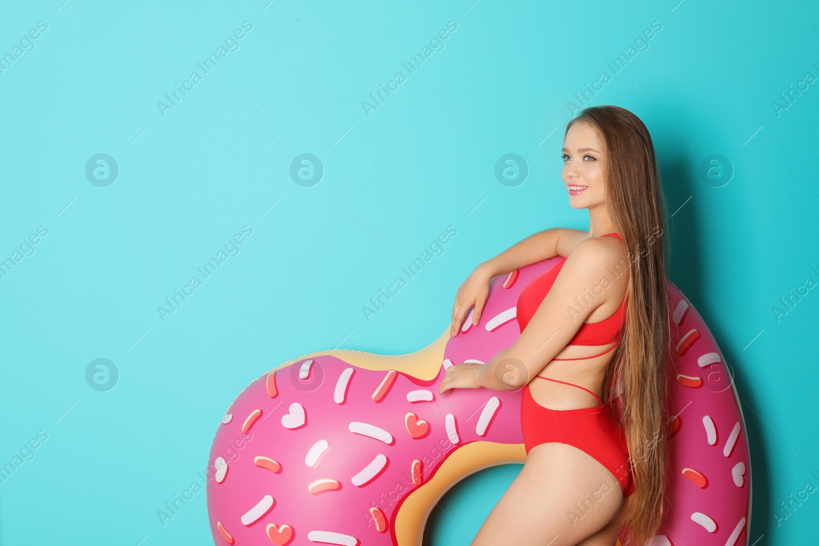 Photo of Beautiful woman with inflatable heart wearing bikini on color background