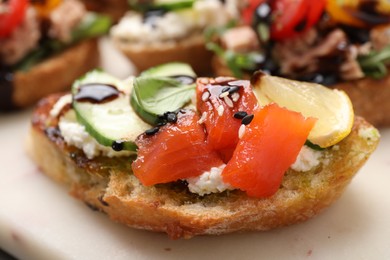 Delicious bruschetta with balsamic vinegar and toppings on white board, closeup