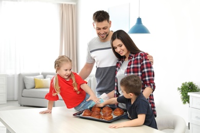 Happy family with tray of oven baked buns in kitchen