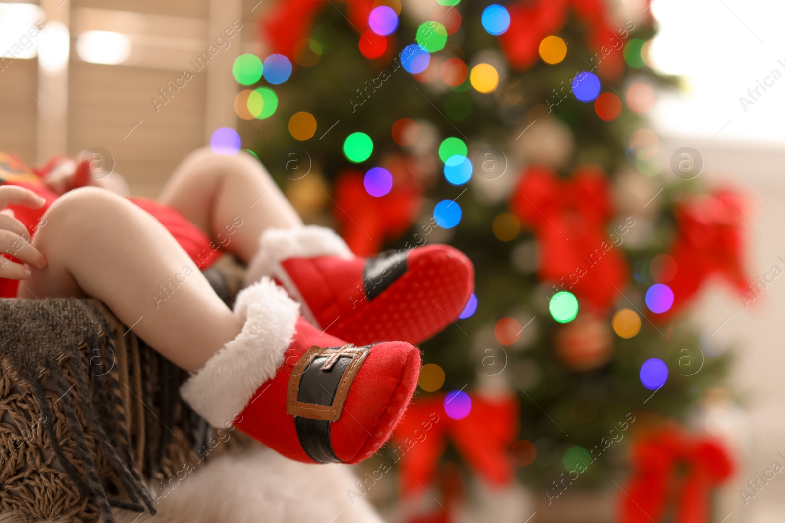 Photo of Cute baby in Christmas costume at home, focus on legs