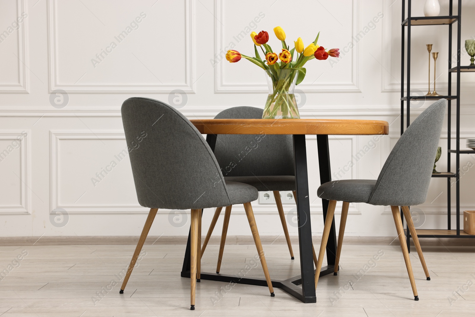 Photo of Stylish dining room interior with comfortable furniture and beautiful tulips