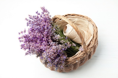 Photo of Wicker basket with lavender flowers and rope on light background