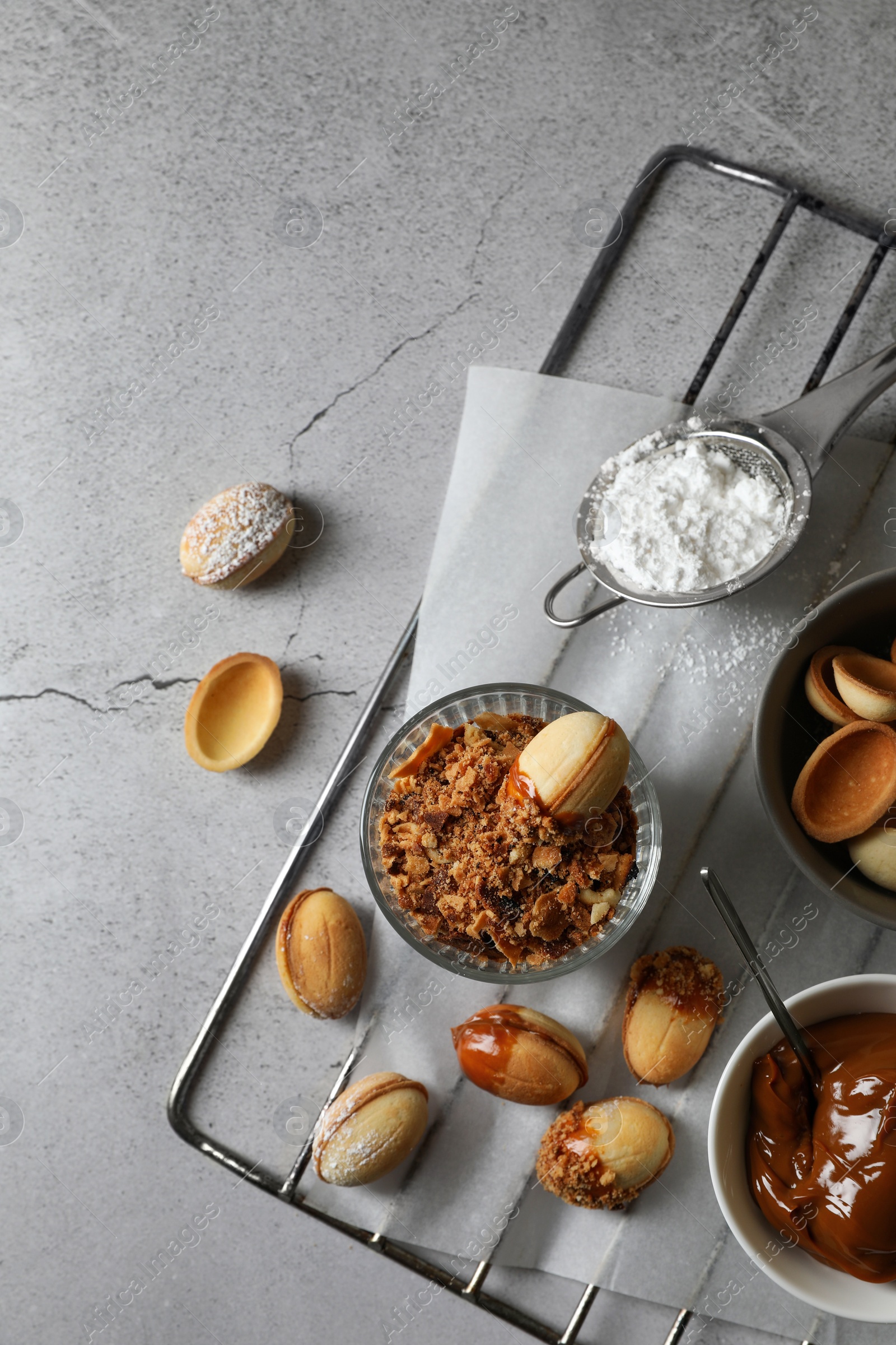 Photo of Delicious walnut shaped cookies with condensed milk on grey table, flat lay