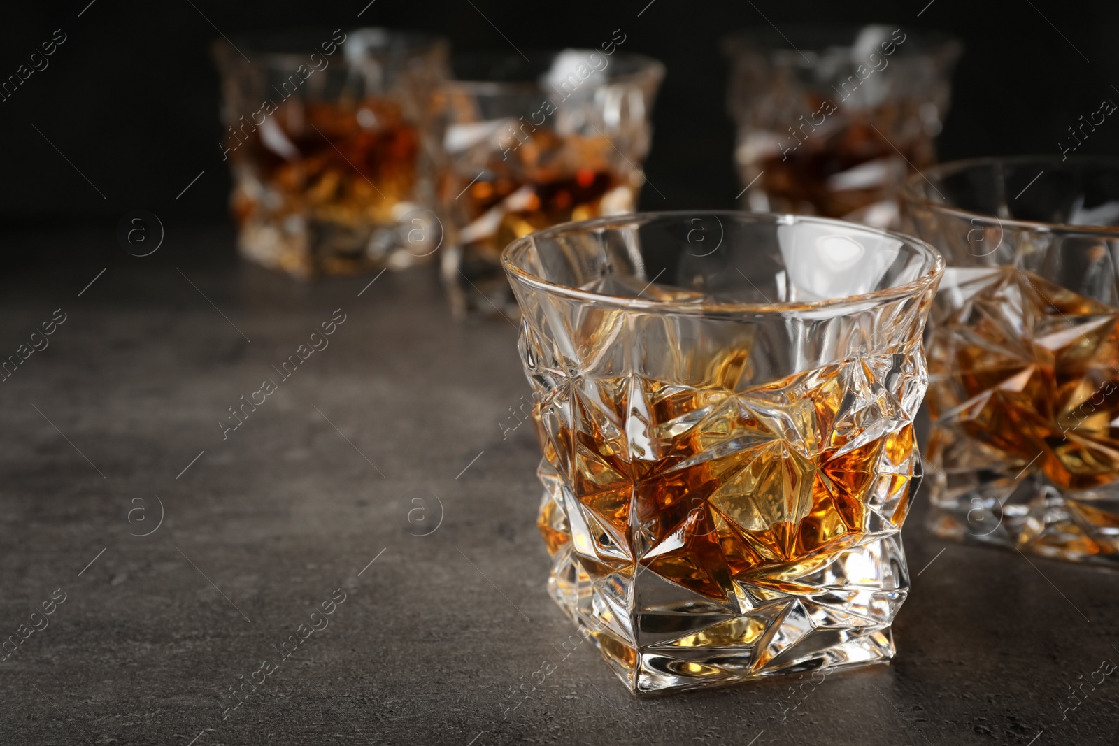 Photo of Golden whiskey in glass with ice cubes on table. Space for text