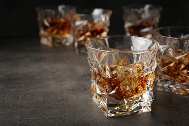 Golden whiskey in glass with ice cubes on table. Space for text