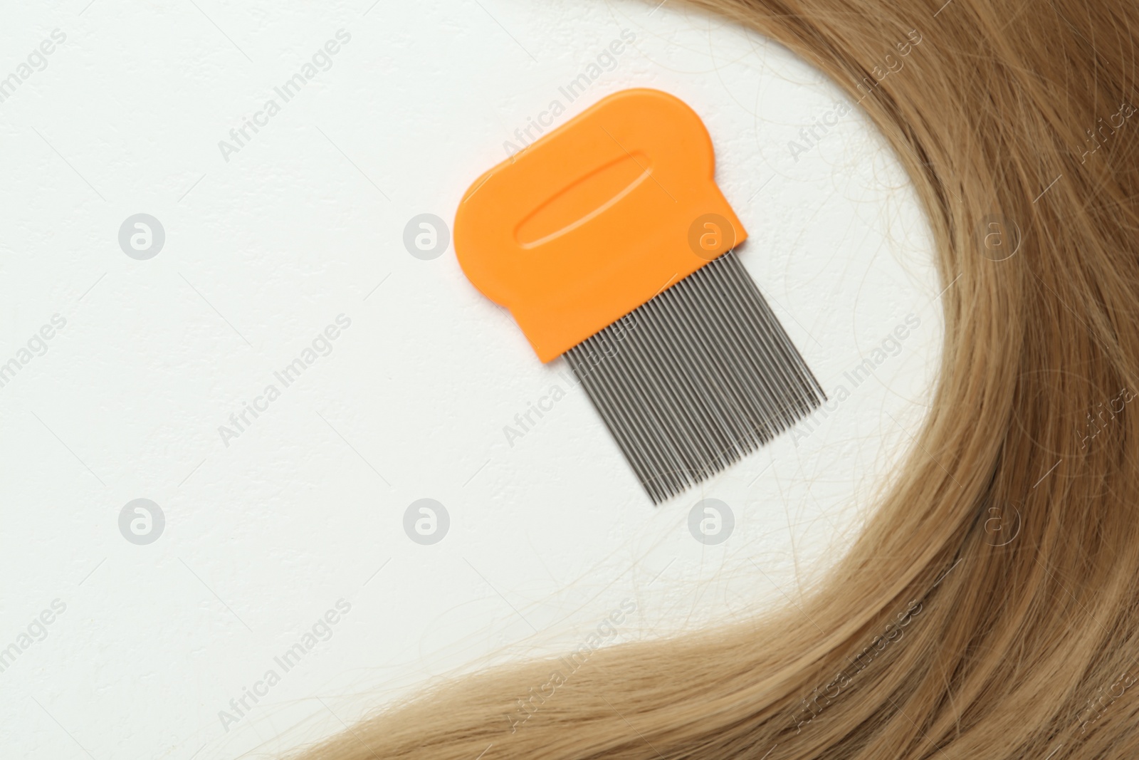 Photo of Metal comb and blond hair on white background, flat lay. Anti lice treatment