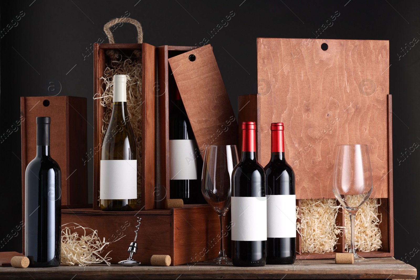 Photo of Different bottles of wine, glasses, wooden boxes, corks and corkscrew on table