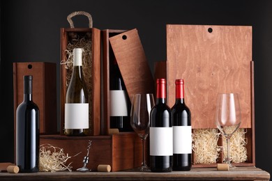 Different bottles of wine, glasses, wooden boxes, corks and corkscrew on table