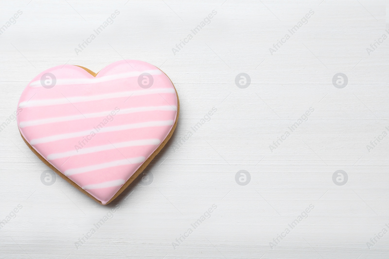 Photo of Heart shaped cookie on white wooden table, top view with space for text. Valentine's day treat