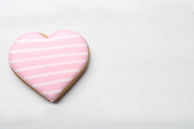 Heart shaped cookie on white wooden table, top view with space for text. Valentine's day treat