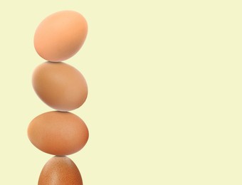 Image of Stacked fresh chicken eggs against light beige background. Space for text