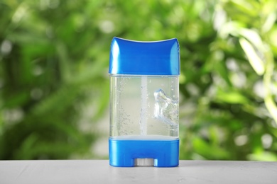 Photo of Deodorant container on white wooden table against blurred background