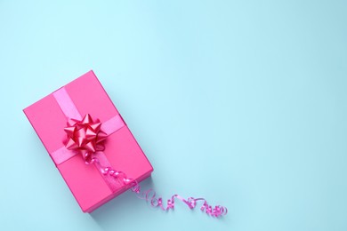 Photo of Pink gift box on light blue background, top view. Space for text