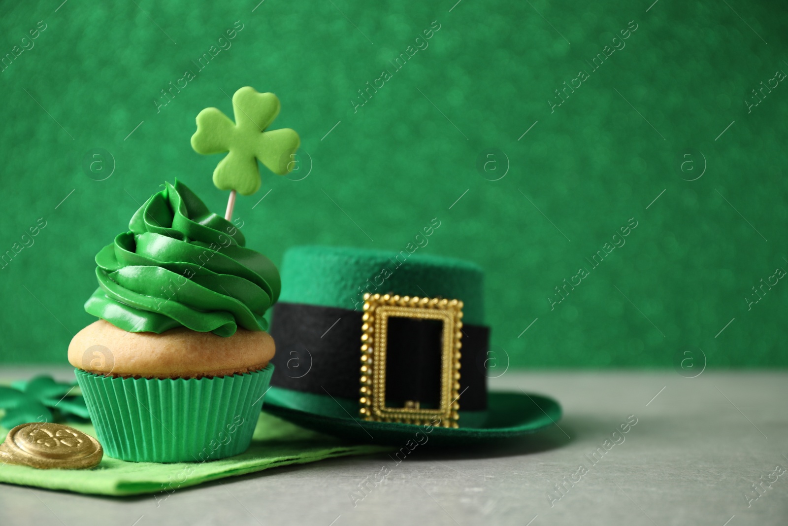 Photo of Decorated cupcake, hat and coins on grey table, space for text. St. Patrick's Day celebration