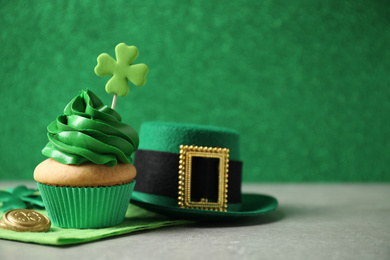 Decorated cupcake, hat and coins on grey table, space for text. St. Patrick's Day celebration