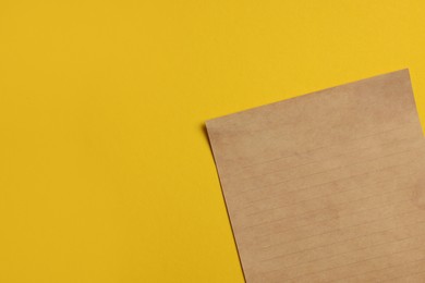 Photo of Sheet of old parchment paper on yellow background, top view. Space for text