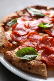 Tasty pepperoni pizza with basil on table, closeup