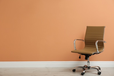 Photo of Modern office chair near orange coral wall indoors. Space for text