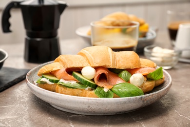 Photo of Plate with tasty croissant sandwich on table
