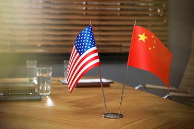 Photo of USA and China flags on wooden table in office. International relations