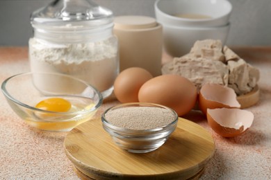 Photo of Compressed and dry granulated yeast, flour and eggs on orange textured table