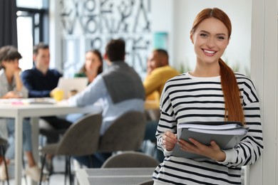 Photo of Team of employees working together in office. Happy woman with folders indoors, space for text