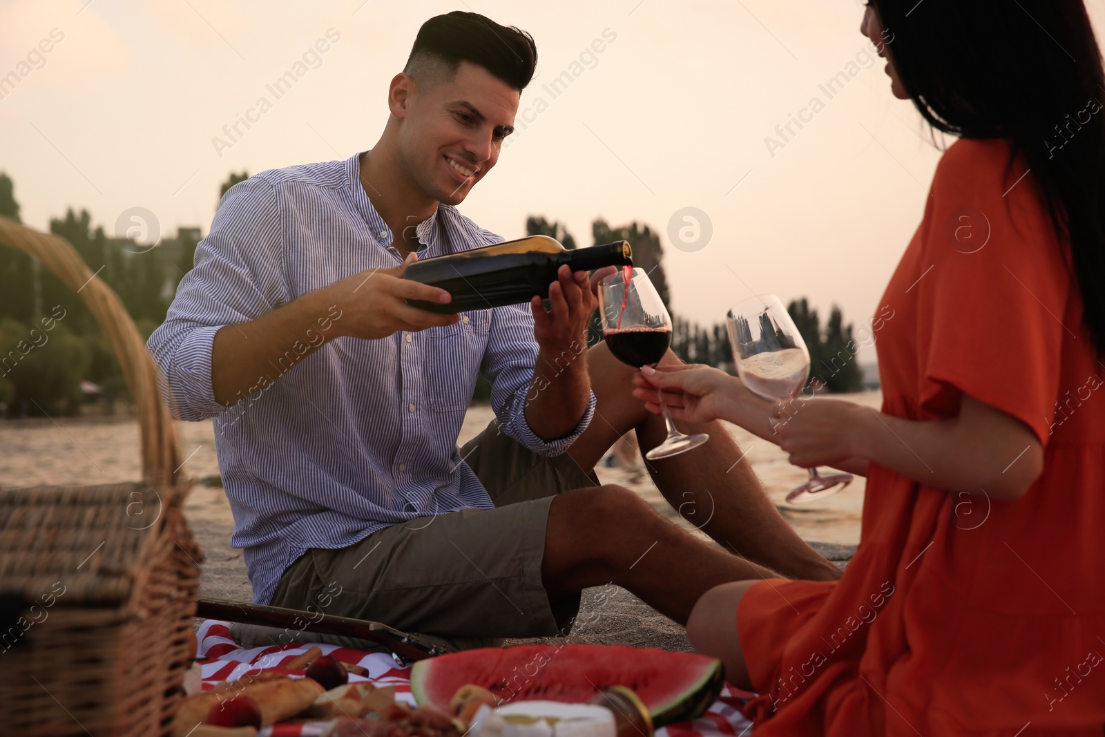 Photo of Lovely couple having picnic near river at sunset