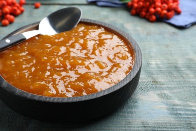 Photo of Delicious rowan jam in bowl on light blue wooden table, closeup