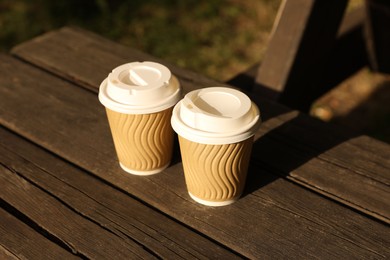Photo of Paper cups on wooden table outdoors. Coffee to go