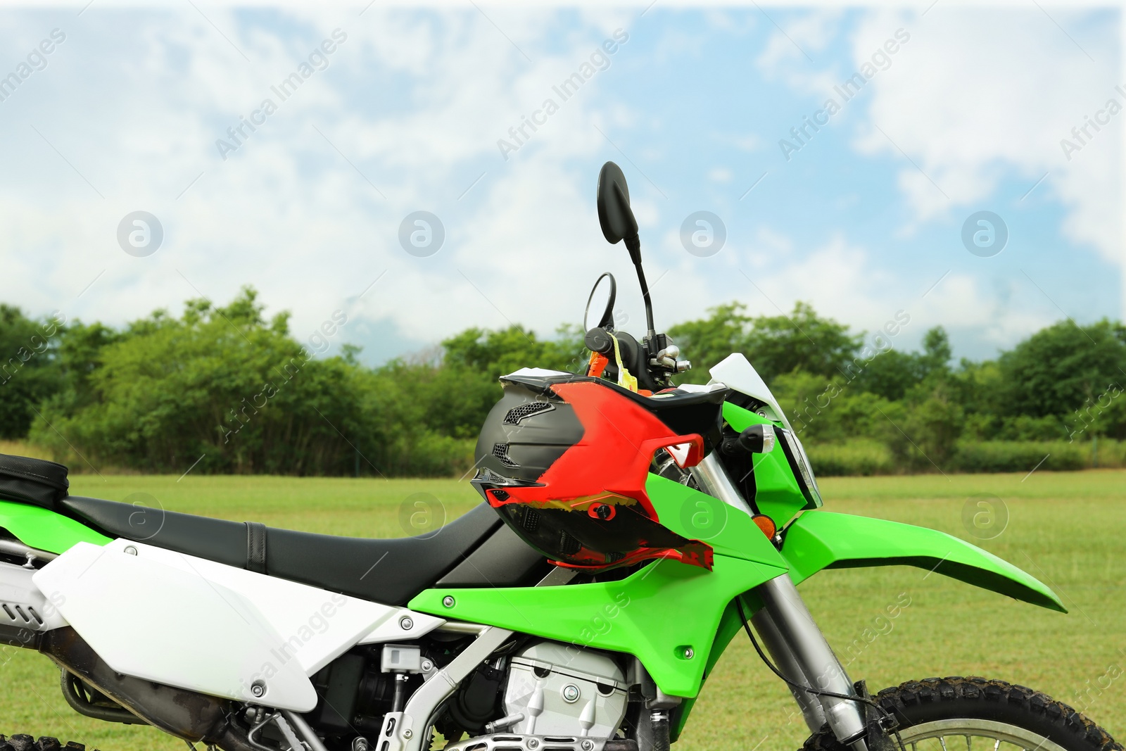 Photo of Stylish green cross motorcycle with helmet outdoors