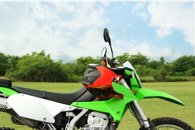 Stylish green cross motorcycle with helmet outdoors