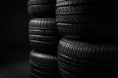 Photo of Stacked car tires on black background, closeup