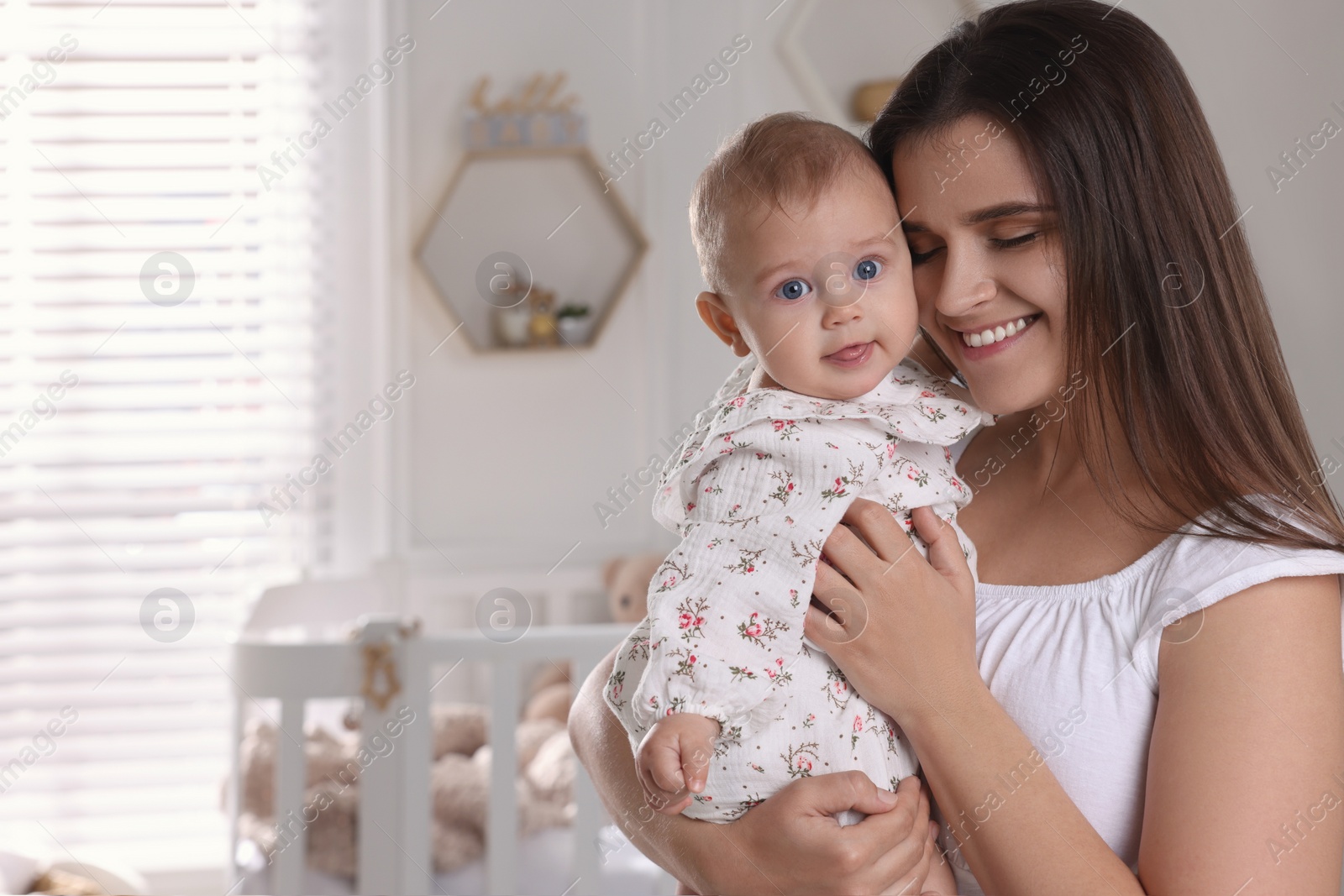 Photo of Happy young mother with her baby daughter in nursery. Space for text