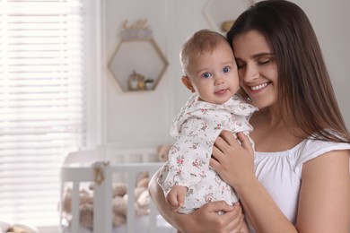 Photo of Happy young mother with her baby daughter in nursery. Space for text