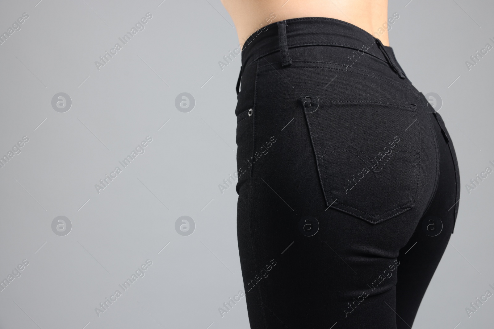 Photo of Woman wearing stylish black jeans on light gray background, closeup. Space for text