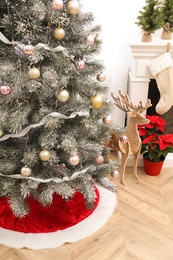 Beautifully decorated Christmas tree with skirt indoors