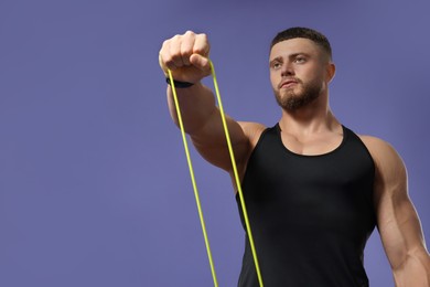 Photo of Muscular man exercising with elastic resistance band on purple background, low angle view. Space for text