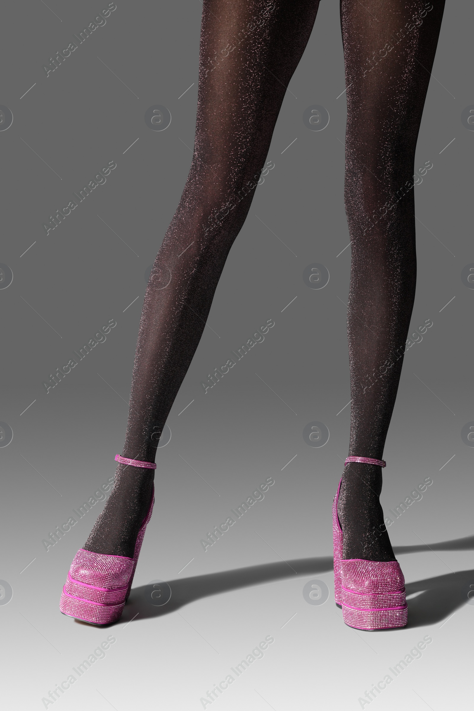 Photo of Woman wearing pink high heeled shoes with platform and square toes on light grey background, closeup