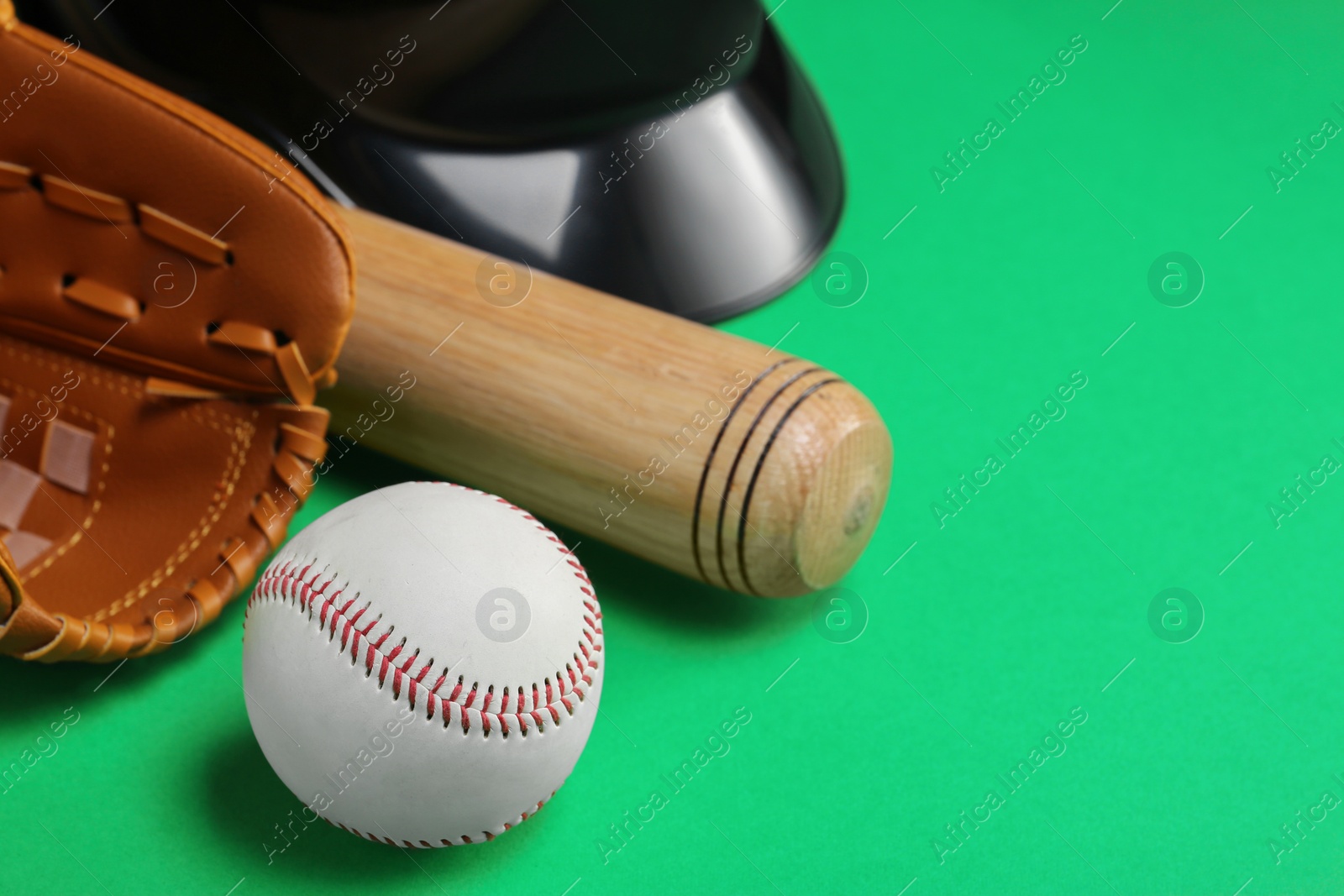 Photo of Baseball glove, bat and ball on green background, closeup. Space for text