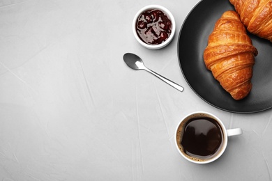 Flat lay composition with cup of coffee, jam and croissants on light background. Space for text
