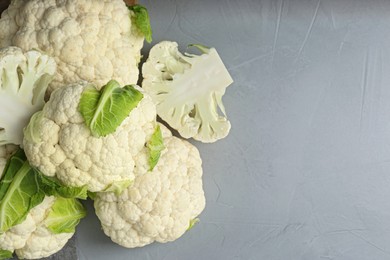 Photo of Fresh whole and cut cauliflowers on light grey table, top view. Space for text