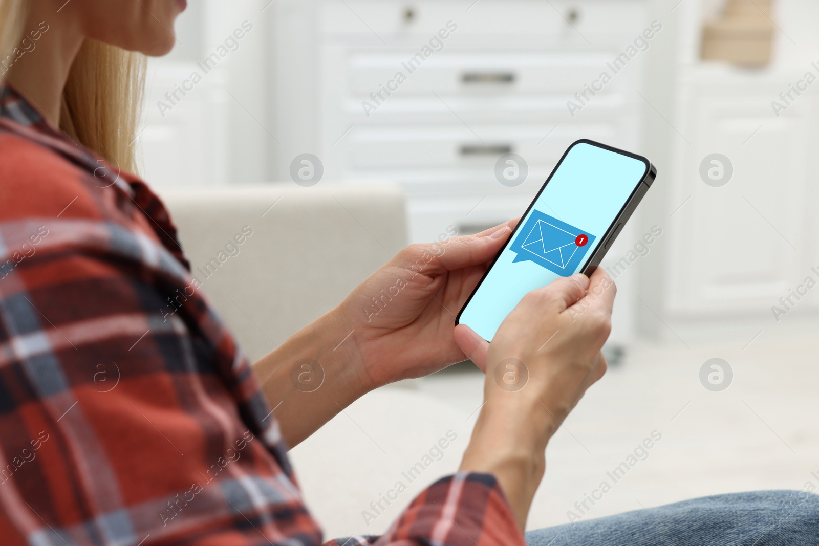 Image of Woman received message on mobile phone indoors, closeup. Envelope illustration on device screen