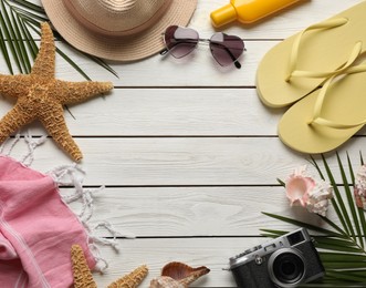 Frame of different beach objects on white wooden background, flat lay. Space for text