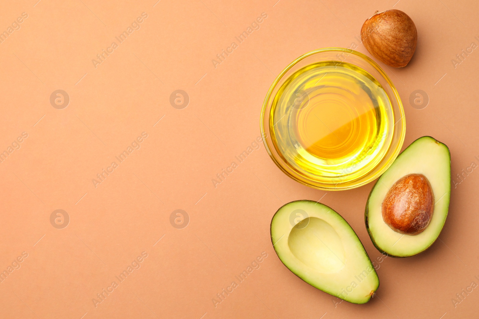 Photo of Cooking oil in bowl and fresh avocados on beige background, flat lay. Space for text