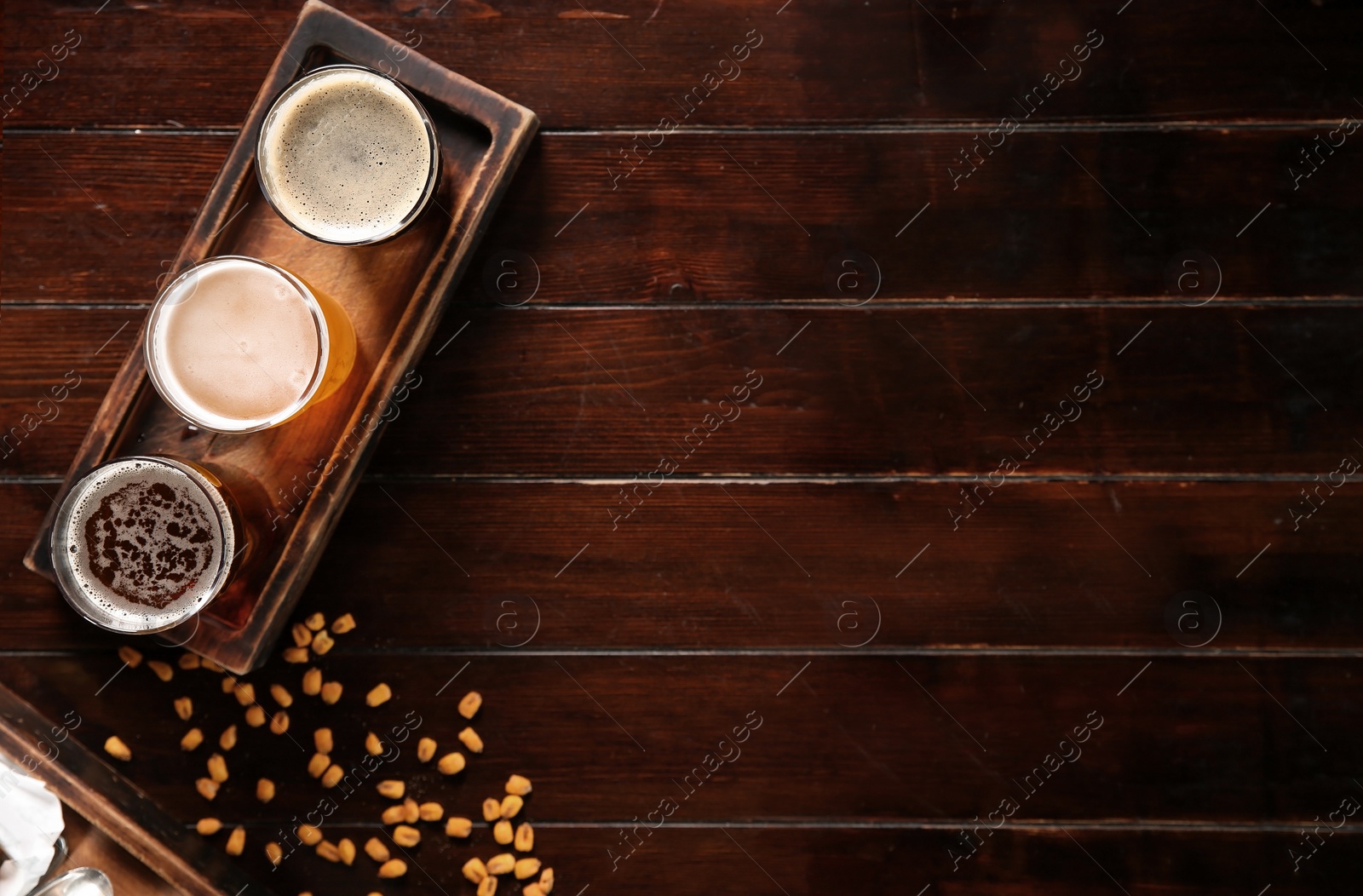 Photo of Glasses of tasty beer and snacks on wooden table