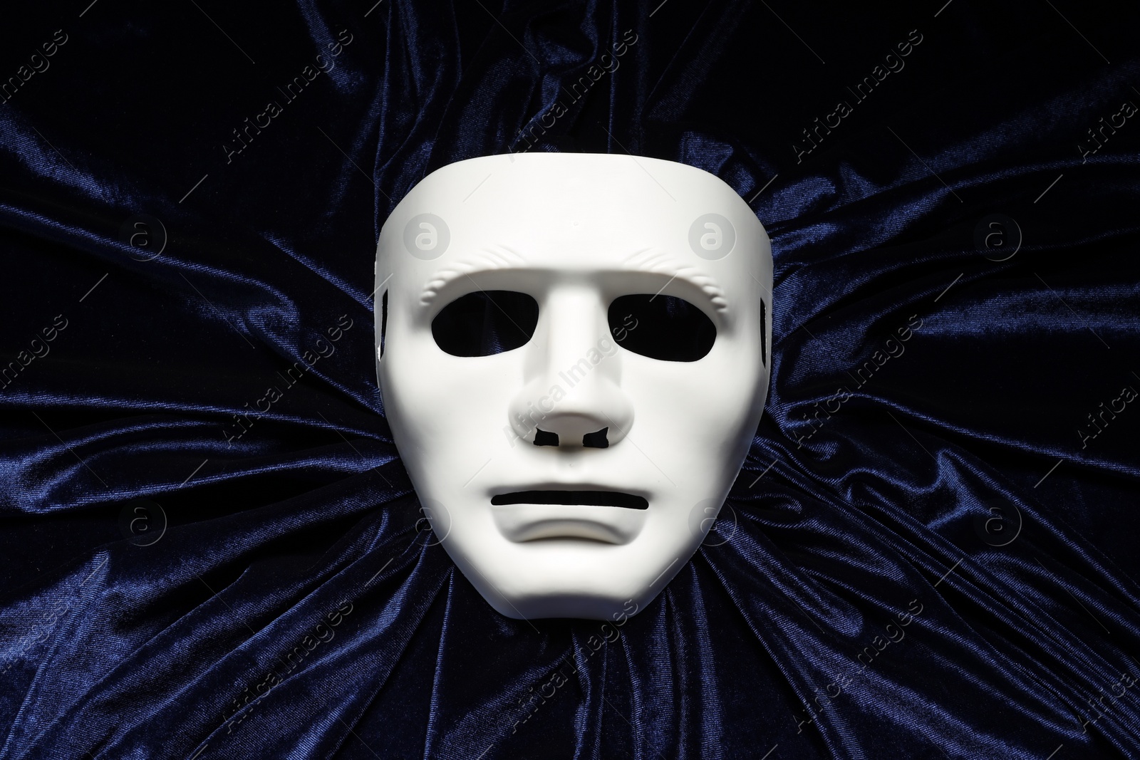 Photo of Theater arts. White mask on blue fabric, top view