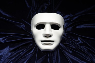 Theater arts. White mask on blue fabric, top view