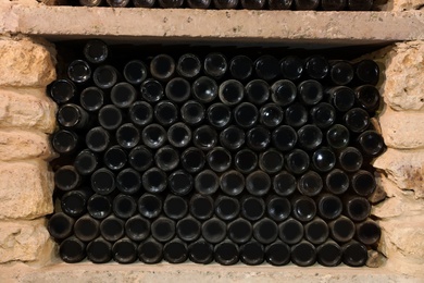 Photo of Many wine bottles on shelf in cellar