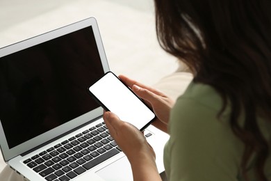 Photo of Young woman with smartphone and laptop indoors, closeup